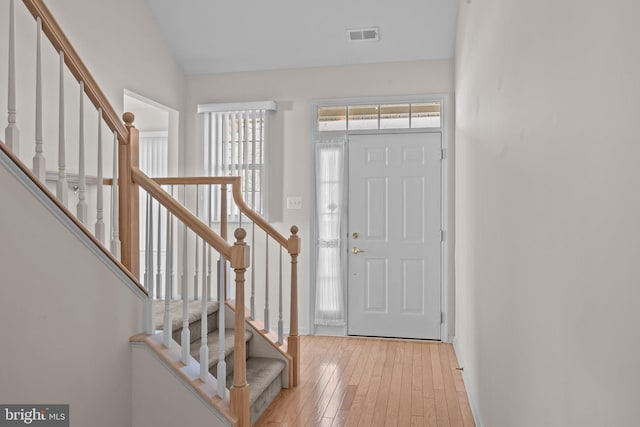 entrance foyer with stairway, baseboards, visible vents, and light wood finished floors