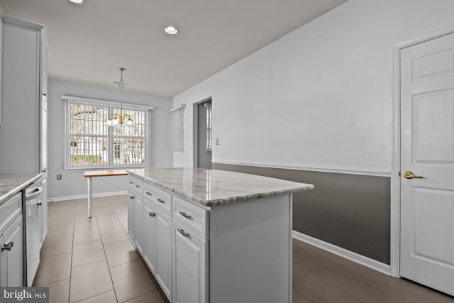 kitchen featuring light stone countertops, baseboards, a kitchen island, stainless steel dishwasher, and decorative light fixtures