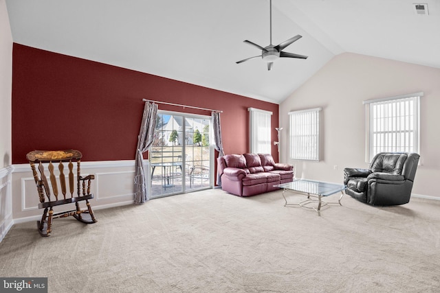 living room with a ceiling fan, visible vents, carpet floors, vaulted ceiling, and wainscoting