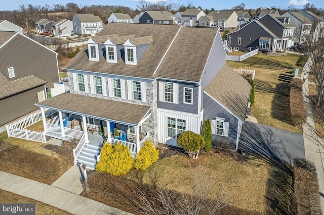 view of front of home with covered porch, fence, a residential view, and a shingled roof