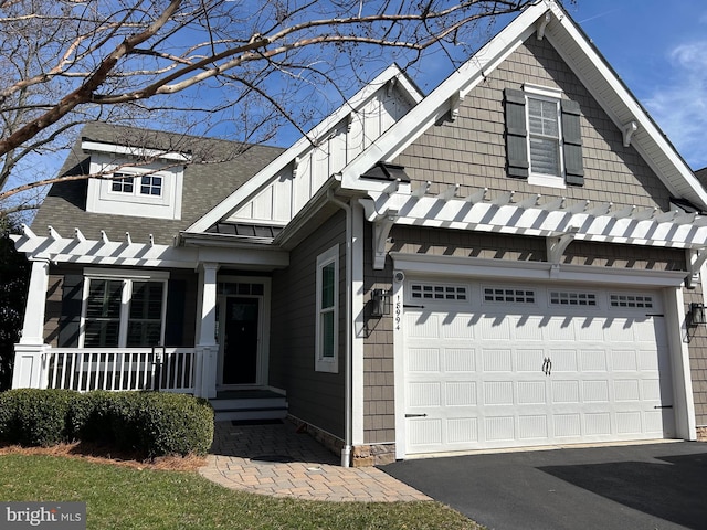 view of front of property featuring board and batten siding, aphalt driveway, covered porch, and roof with shingles