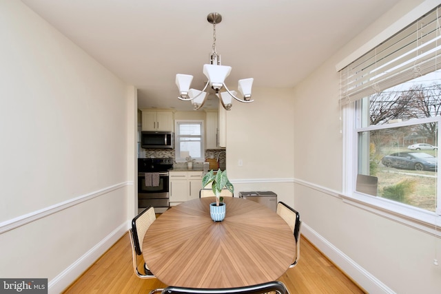 dining area featuring a notable chandelier, baseboards, and light wood-type flooring