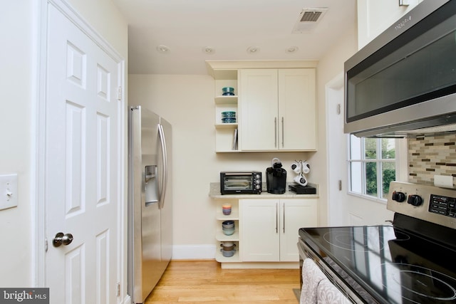 kitchen with visible vents, open shelves, stainless steel appliances, light wood-style floors, and white cabinets