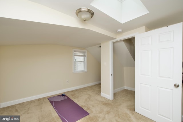 workout room with baseboards, light colored carpet, and vaulted ceiling