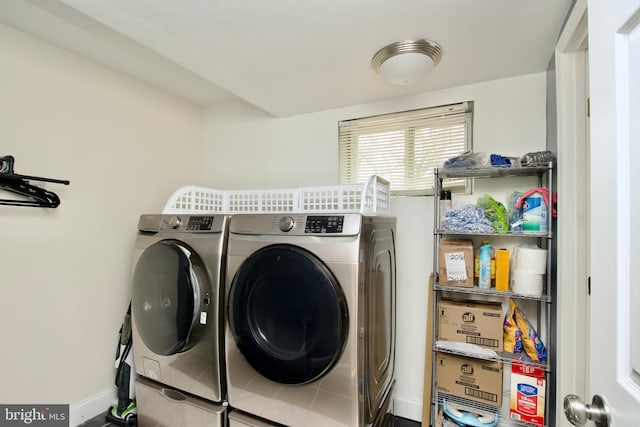 clothes washing area featuring baseboards, separate washer and dryer, and laundry area