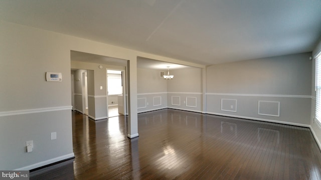 unfurnished room with dark wood-type flooring and an inviting chandelier