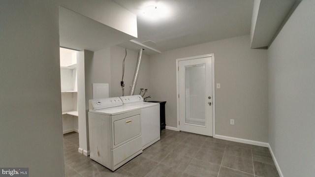 clothes washing area with laundry area, baseboards, and washer and clothes dryer