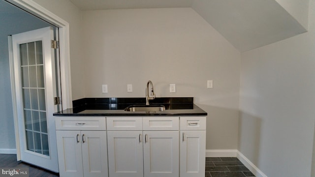 interior space featuring vaulted ceiling, baseboards, and a sink