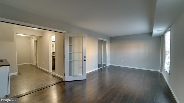 spare room featuring visible vents, baseboards, and dark wood-style flooring