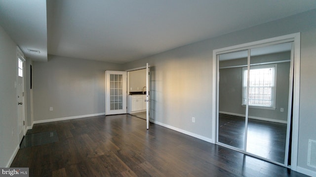 unfurnished bedroom with dark wood-type flooring, visible vents, baseboards, and a closet