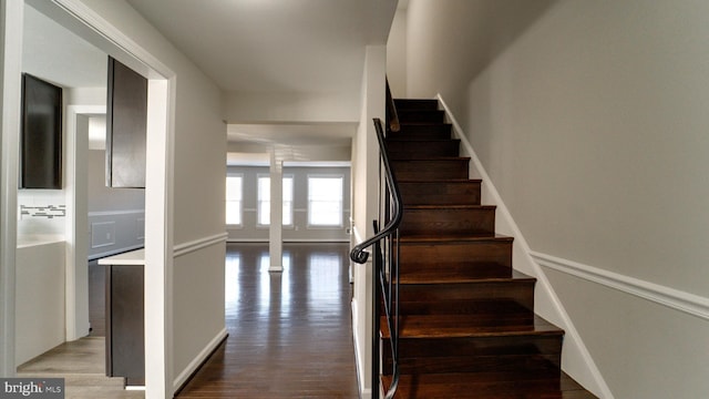 staircase featuring wood finished floors and ornate columns