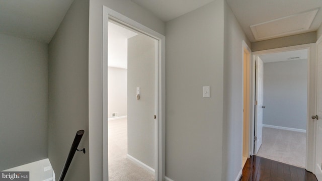 hallway with baseboards, an upstairs landing, attic access, and dark wood-style flooring