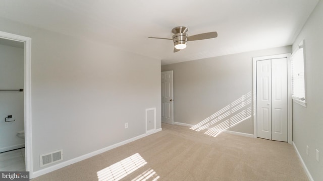 unfurnished room with light carpet, visible vents, ceiling fan, and baseboards