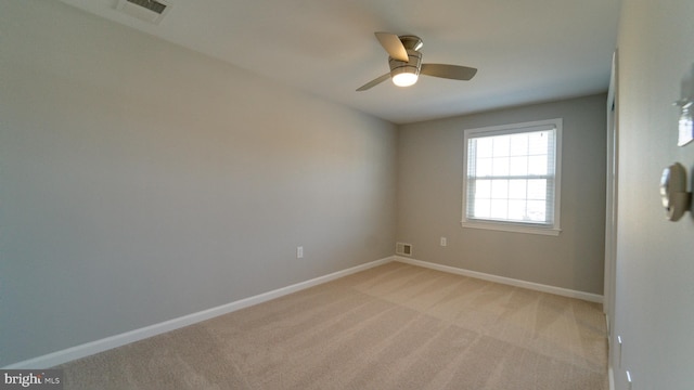 empty room with visible vents, light carpet, baseboards, and a ceiling fan