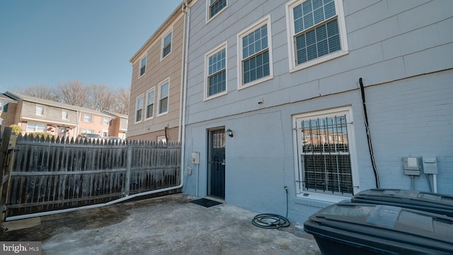 view of side of home with a patio area, brick siding, and fence