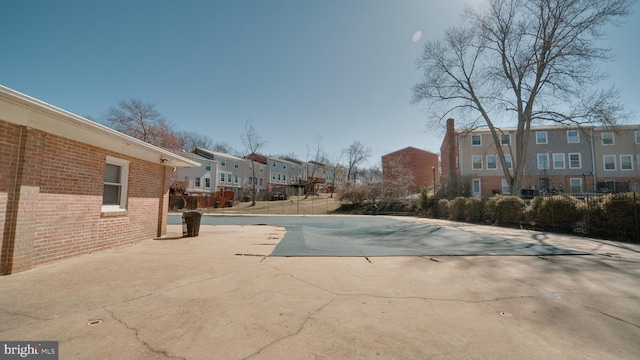 community pool with a residential view, fence, and a patio area