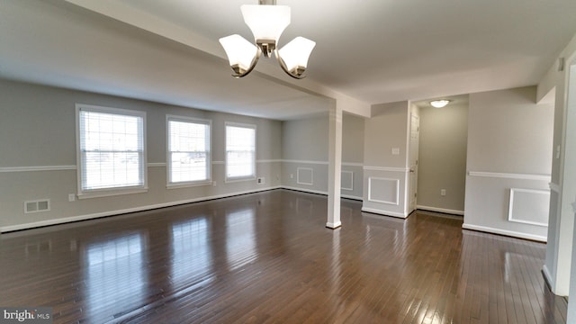 spare room with a chandelier, visible vents, and dark wood-type flooring