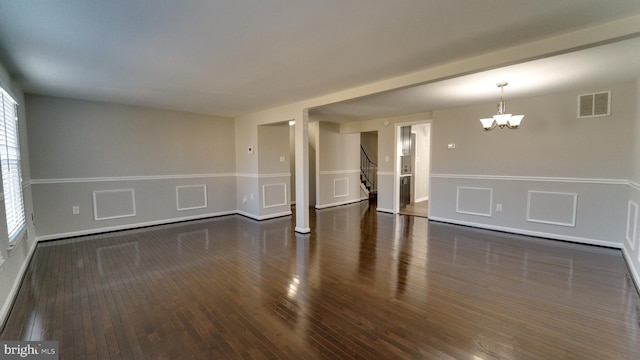 spare room featuring visible vents, a wainscoted wall, stairway, an inviting chandelier, and wood finished floors