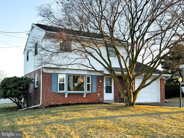 traditional-style home with a garage, brick siding, a front lawn, and aphalt driveway