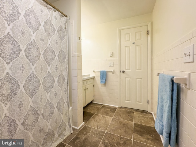 bathroom with a shower with shower curtain, wainscoting, tile walls, and vanity