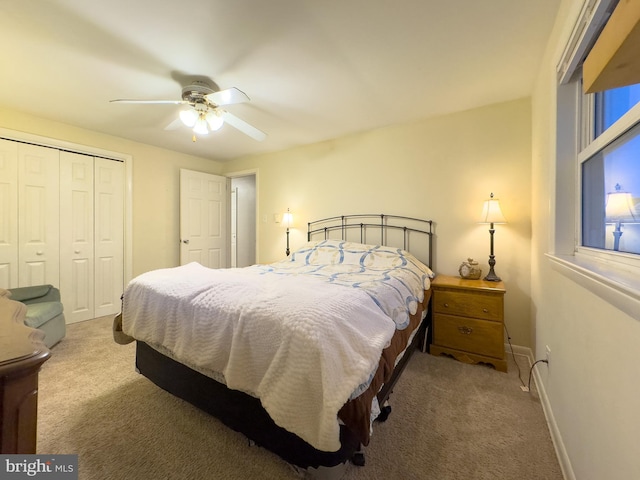 carpeted bedroom featuring a ceiling fan, a closet, and baseboards