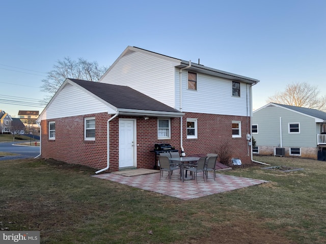 back of property with a patio area, a yard, cooling unit, and brick siding