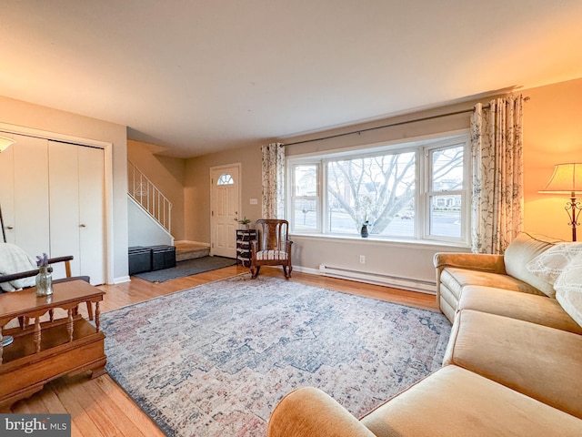 living room featuring stairway, baseboard heating, wood finished floors, and baseboards