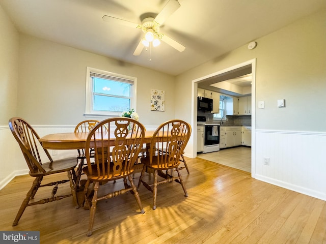 dining room featuring light wood-style floors, a wealth of natural light, wainscoting, and ceiling fan