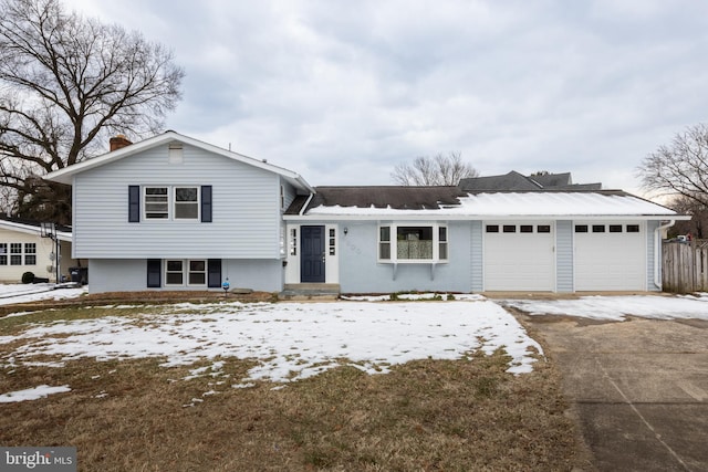 tri-level home with driveway, a chimney, and an attached garage