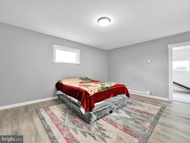 bedroom with baseboards, baseboard heating, and wood finished floors