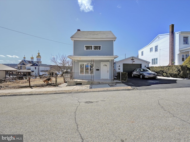 view of front of home featuring an outbuilding, covered porch, a detached garage, and fence