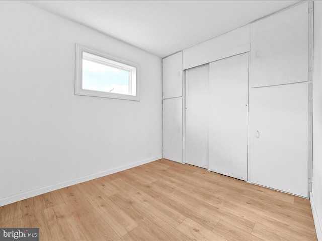 unfurnished bedroom featuring a closet, baseboards, and light wood finished floors