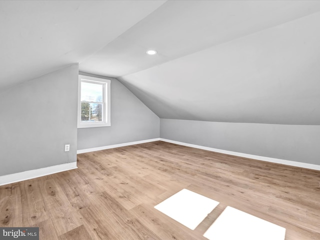 additional living space with lofted ceiling with skylight, recessed lighting, wood finished floors, and baseboards