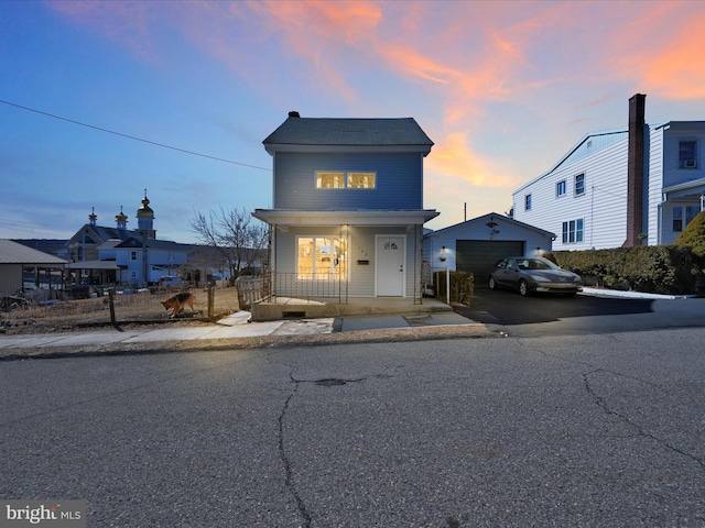 view of front of property featuring a garage, a porch, an outdoor structure, and aphalt driveway