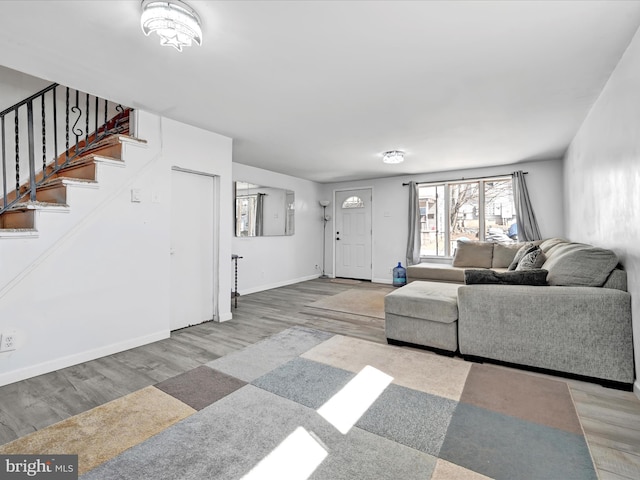 living area featuring baseboards, stairway, and wood finished floors