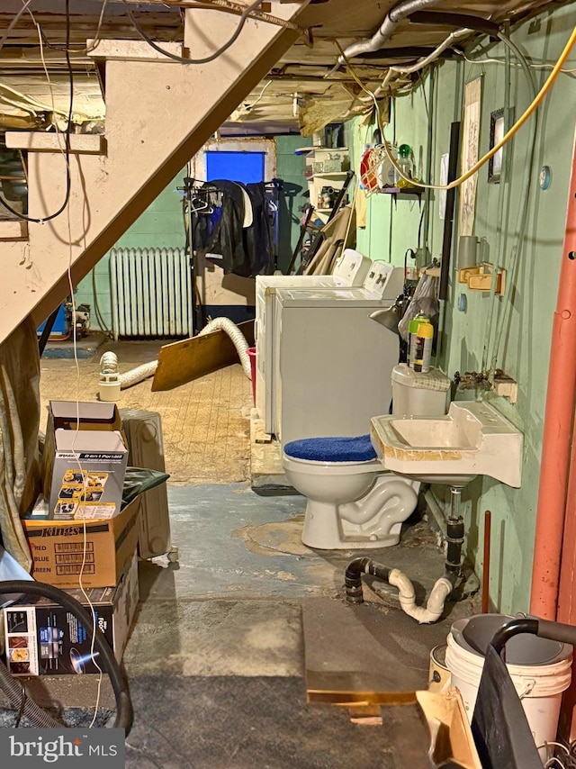 unfinished basement with washer and dryer, a sink, and radiator heating unit