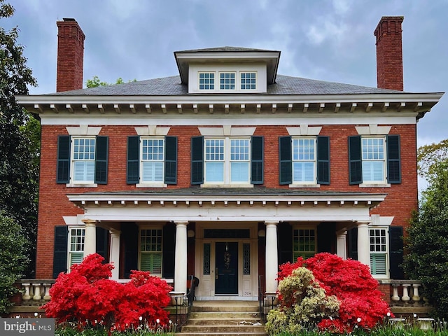 georgian-style home featuring brick siding and covered porch