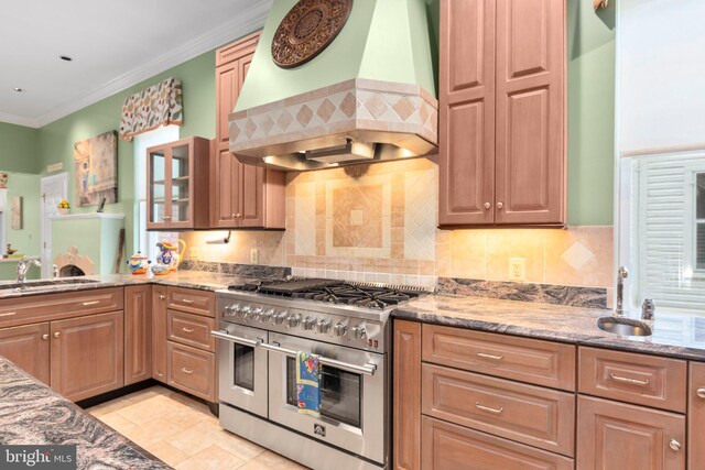 kitchen featuring crown molding, custom range hood, light stone counters, and range with two ovens