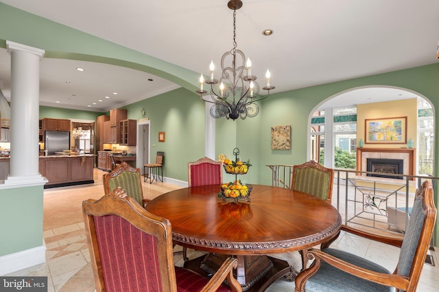 dining space with a tiled fireplace, recessed lighting, arched walkways, baseboards, and a chandelier