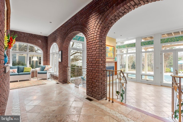 interior space with arched walkways, visible vents, brick wall, and stone tile flooring