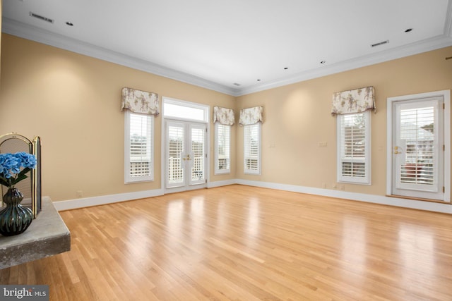 unfurnished living room with a wealth of natural light, visible vents, and crown molding