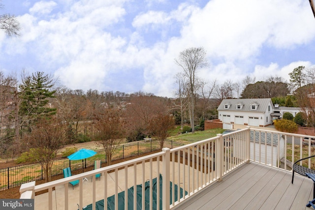 wooden terrace with an outdoor structure, a pool, fence, and a detached garage