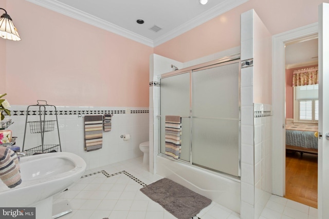 full bathroom with crown molding, toilet, tile patterned floors, combined bath / shower with glass door, and tile walls