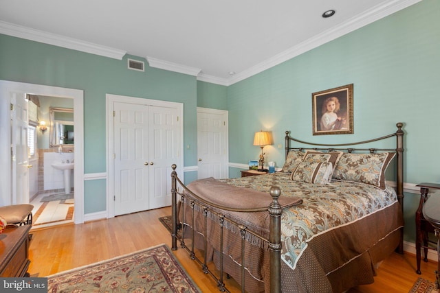 bedroom with visible vents, ensuite bathroom, wood finished floors, a closet, and crown molding