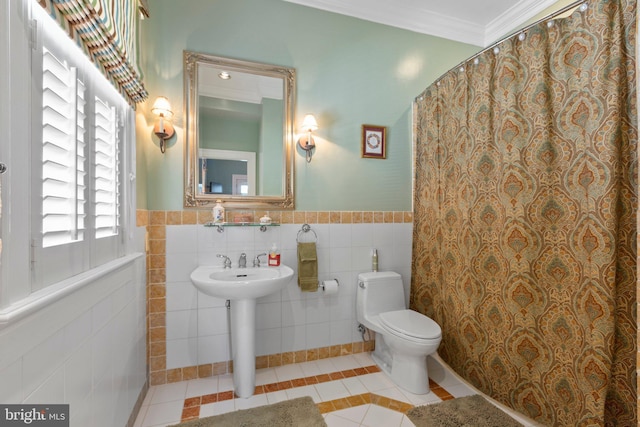 bathroom with a wainscoted wall, ornamental molding, tile patterned floors, toilet, and tile walls