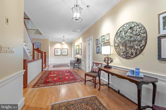 foyer with a wainscoted wall, crown molding, stairs, and wood finished floors