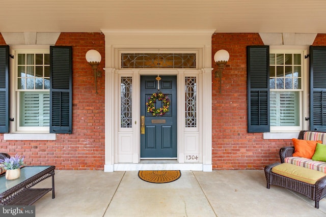 property entrance with brick siding and a porch