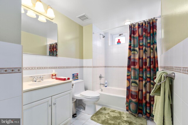 bathroom with a wainscoted wall, visible vents, tile patterned flooring, tile walls, and shower / tub combo with curtain