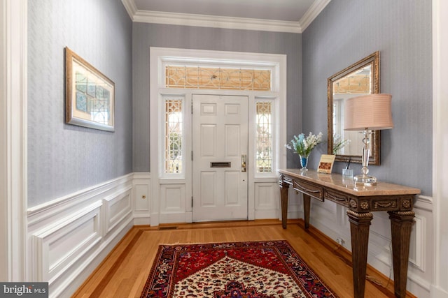 entryway featuring wallpapered walls, a wainscoted wall, and ornamental molding