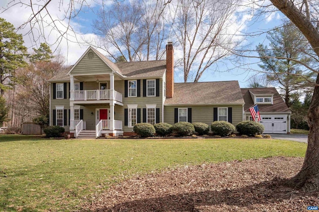 view of front facade featuring an outbuilding, a chimney, a balcony, and a front lawn